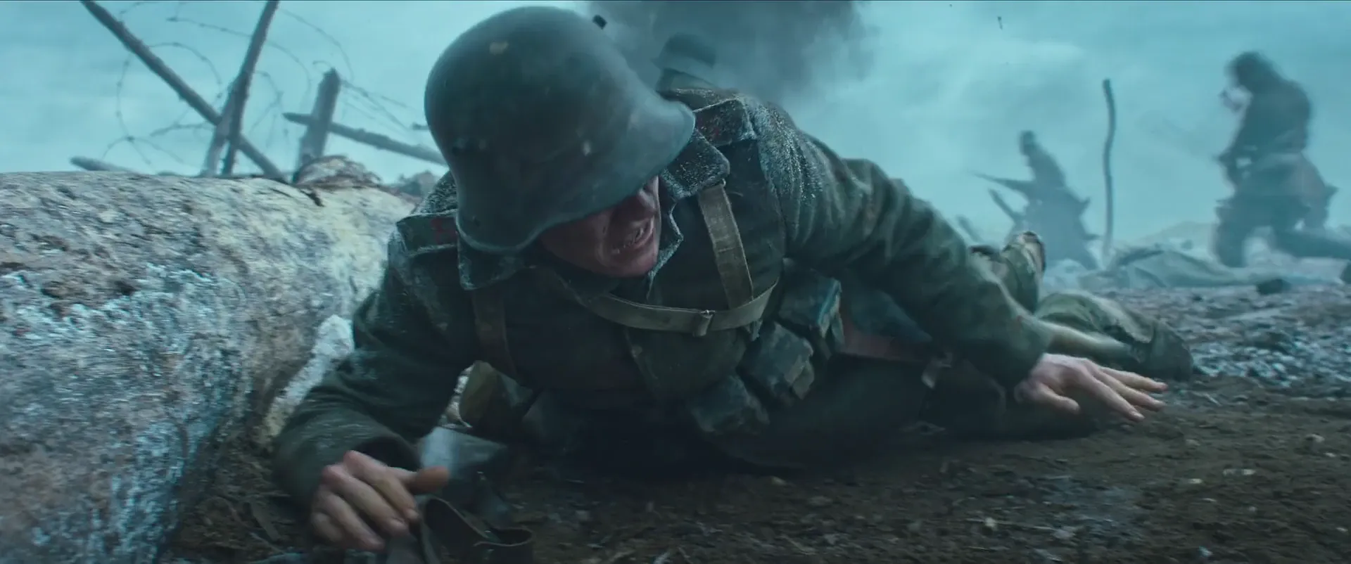 A soldier crawling low through mud and barbed wire in the middle of the battle, All Quiet on the Western Front (2022)