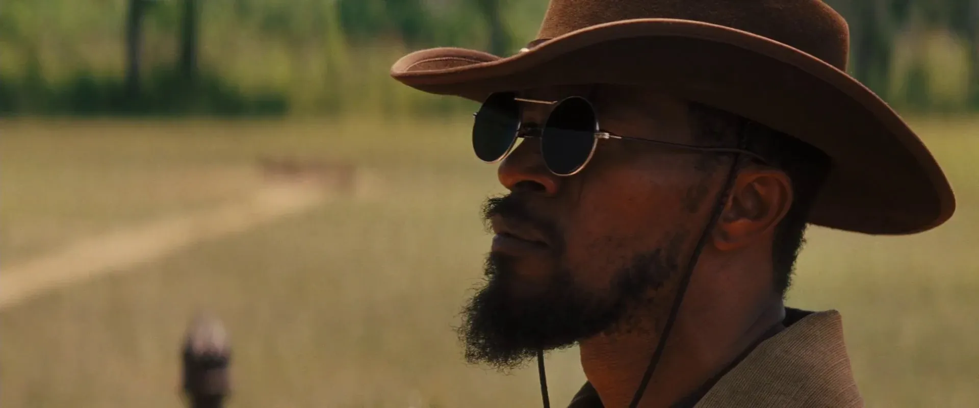 Django Unchained (2012) β hard warm light rims the hat brim and profile against a soft field