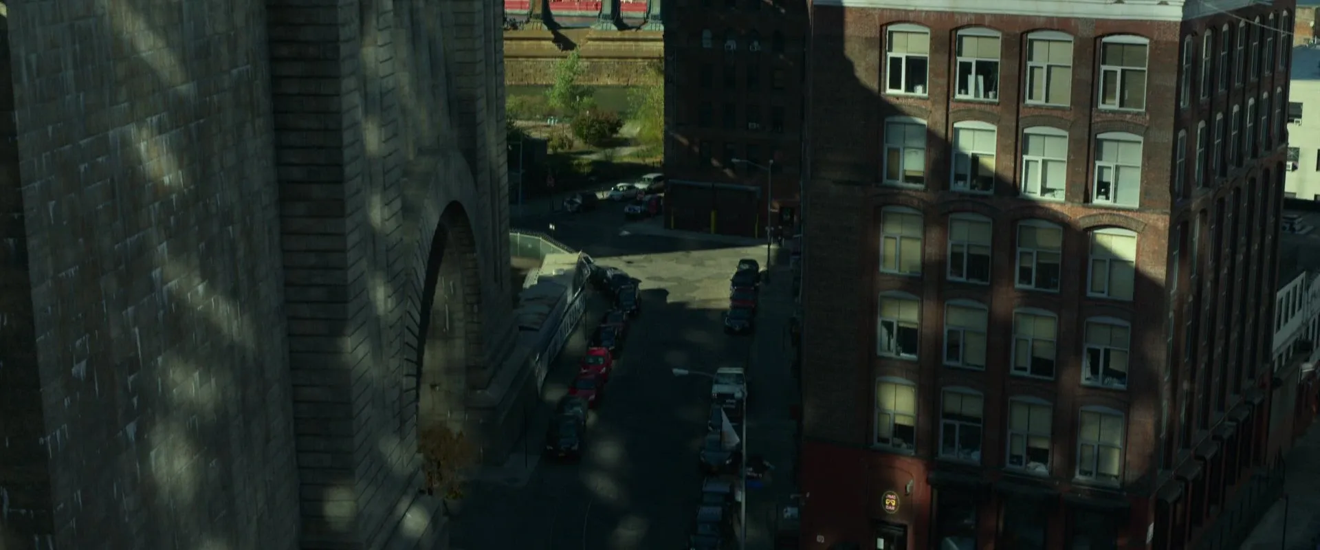 A high, elevated angle looks down a city street beside a stone bridge, revealing the layout of the block below β Gone Girl (2014)