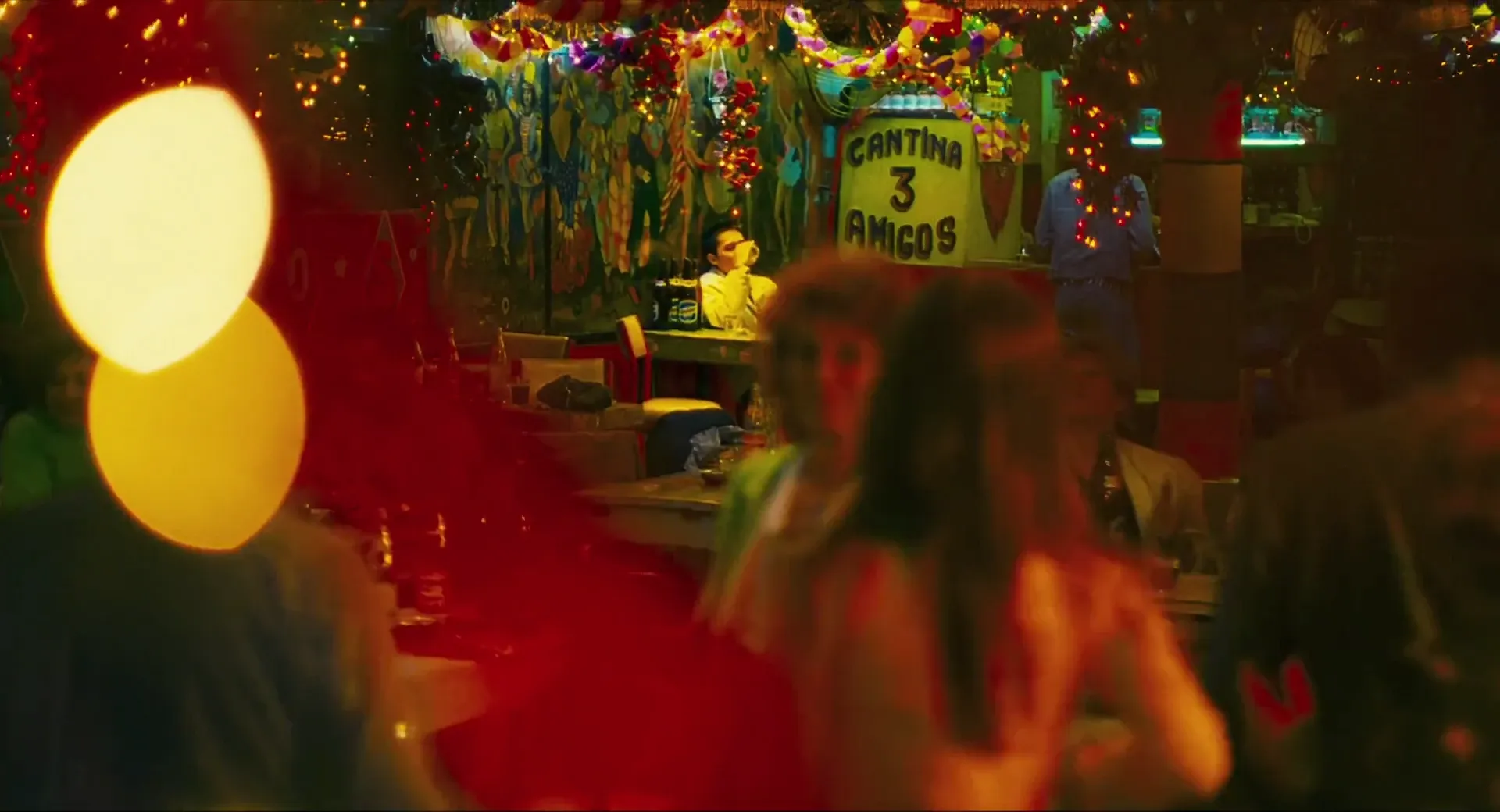 A neon-lit cantina in Happy Together (1997), saturated reds and yellows with out-of-focus figures in the foreground