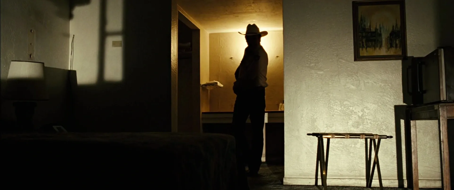No Country for Old Men (2007) β a figure silhouetted in a motel doorway, lit by a single warm source
