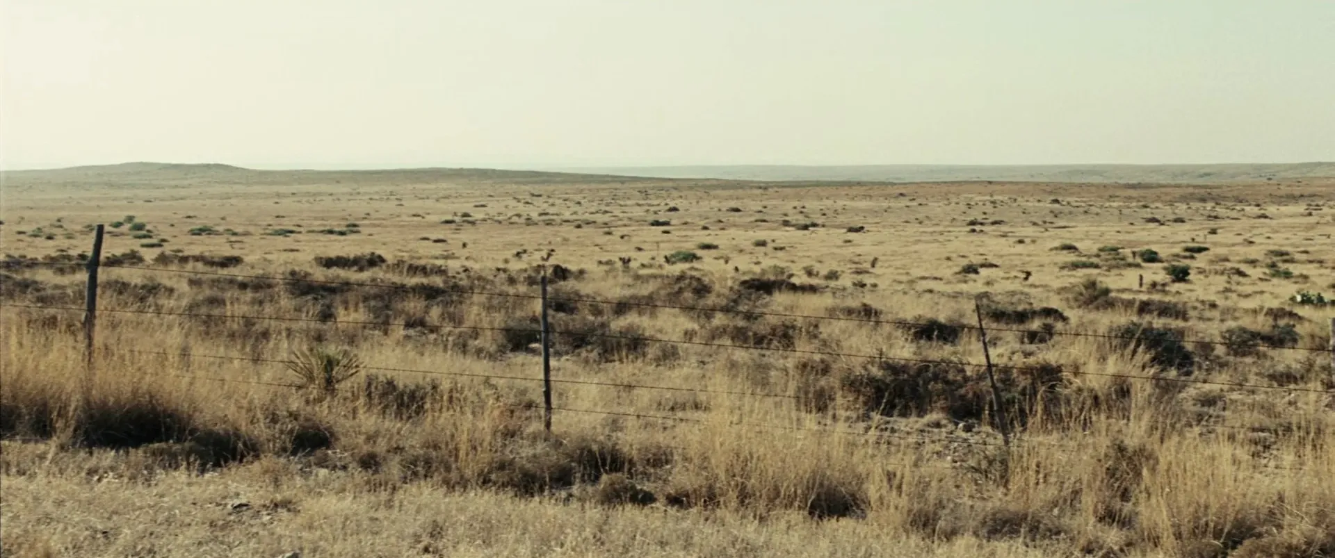 No Country for Old Men (2007) β a barbed-wire fence line across empty, hazy West Texas plains
