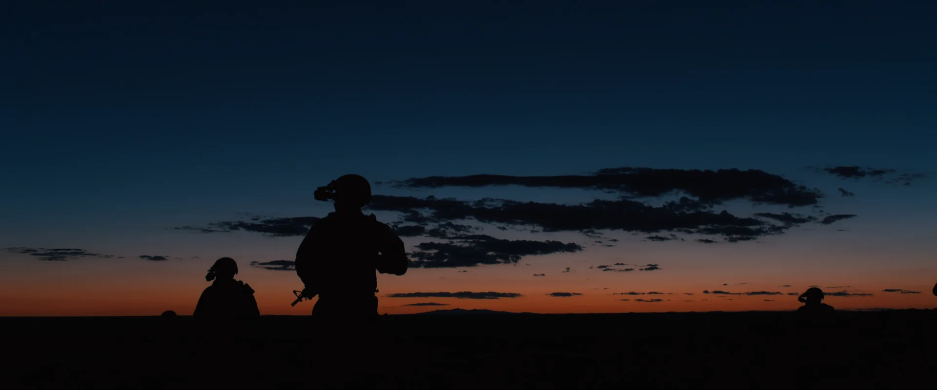 Silhouetted figures on a ridge against a deep blue-to-orange dusk sky, Sicario (2015)