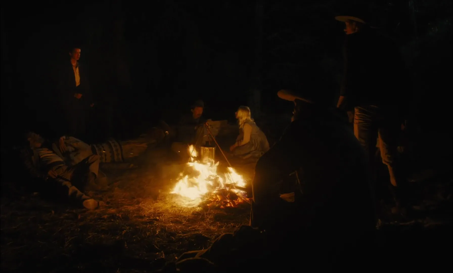 Illustrative frame β a period group around an open fire at night, faces carved out of the dark by the flames themselves (Slow West, 2015)