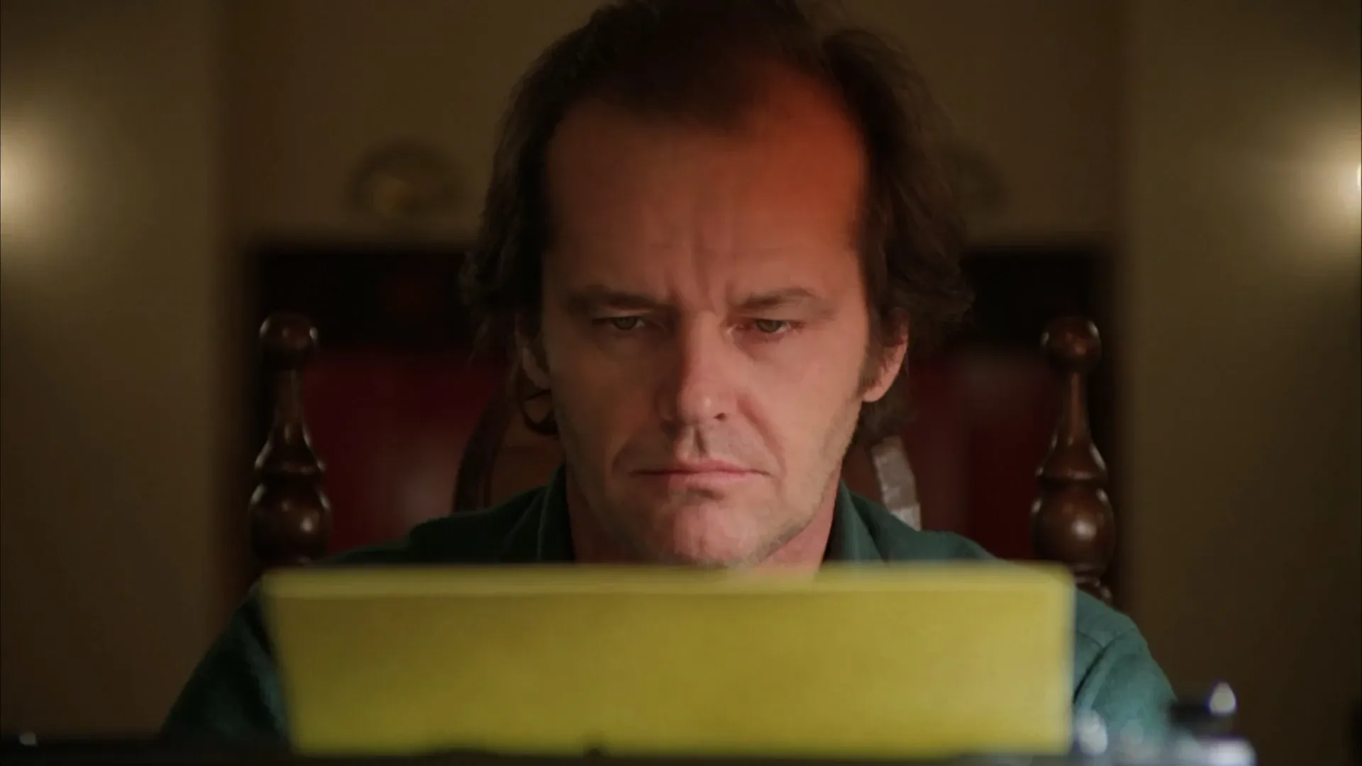 The Shining (1980) — Jack at the typewriter, uplit and frontal, the geometry closing in