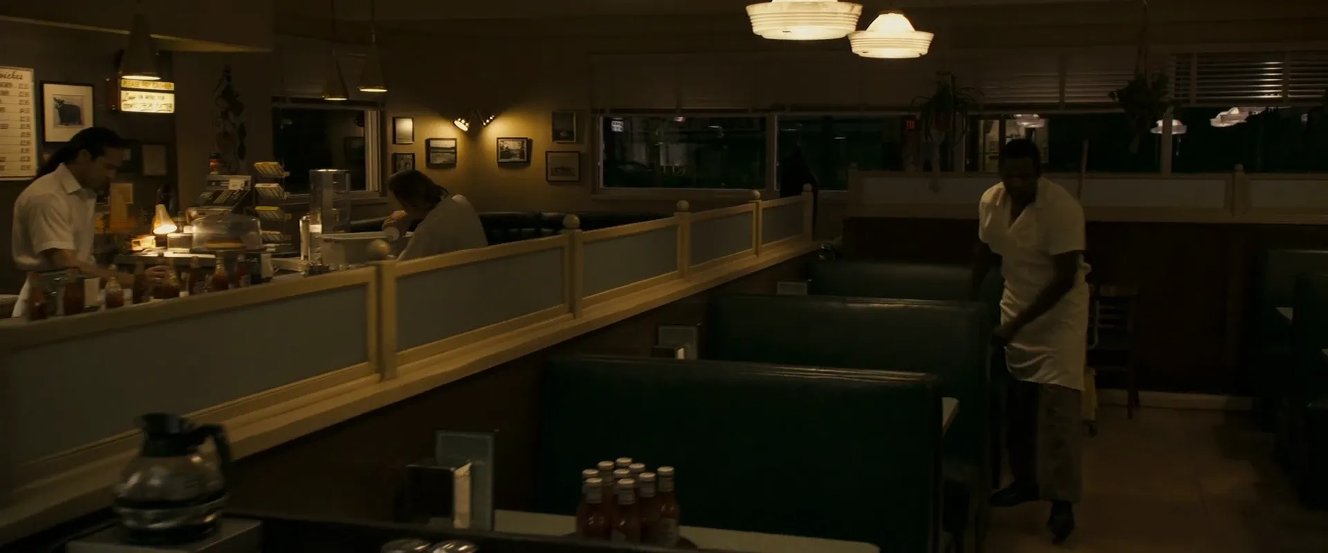 A warm tungsten-lit diner at night, deep amber pooling around the booths β Zodiac (2007)